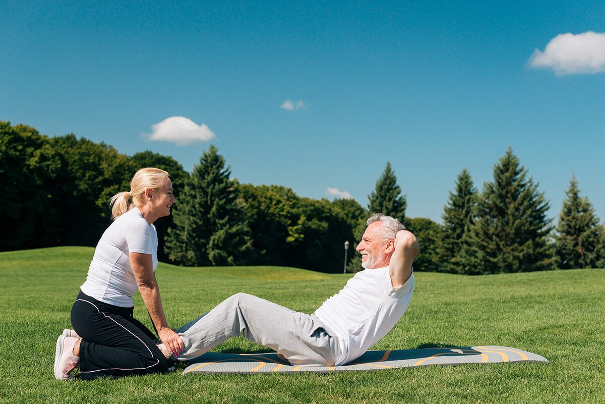 woman-holding-man-while-he-is-doing-crunches (1)